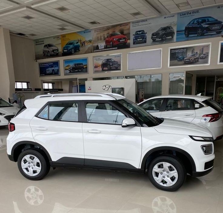 "White Hyundai Venue SUV showroom के बाहर खड़ी हुई, modern exterior design के साथ"