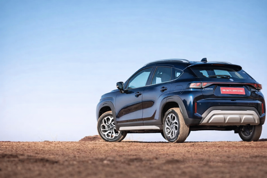 नीले रंग की Maruti Fronx SUV का रियर-साइड व्यू, खुले मैदान में खड़ी हुई HD क्वालिटी कार इमेज, अलॉय व्हील्स और मॉडर्न टेललाइट डिज़ाइन के साथ।