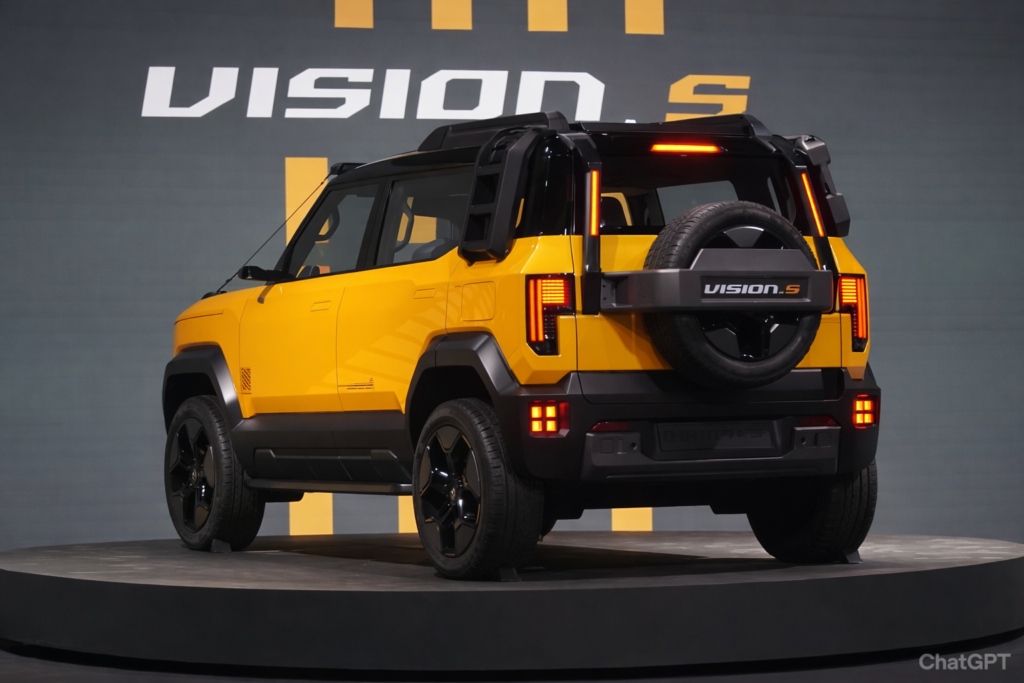 Rear three-quarter view of Mahindra Vision S concept SUV in bright yellow color with black roof, LED tail lamps, and rear-mounted spare wheel displayed on a stage platform.