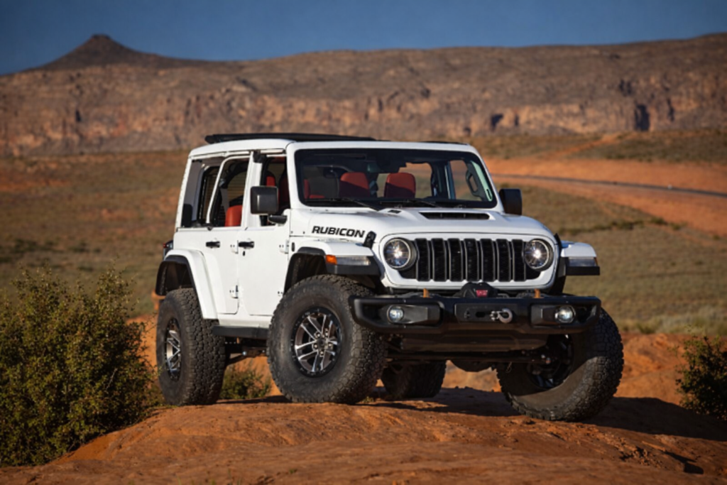 “Registani aur pathrile off-road trail par khadi safed Jeep Rubicon, bade off-road tyres ke saath, peeche pahaadi chattan aur neela aasman.”